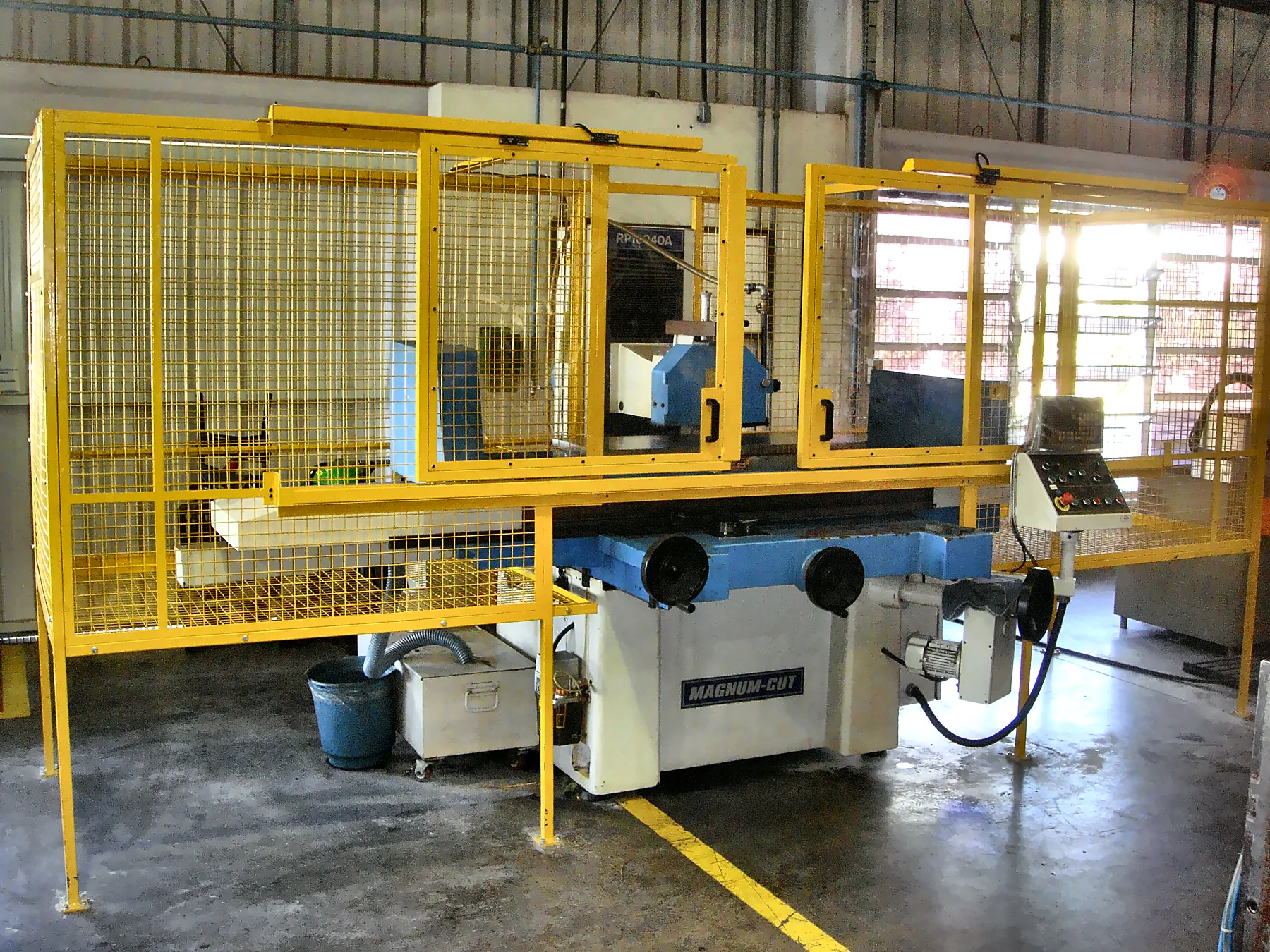 Máquina de ferramentaria com cercamento amarelo, portas de acesso e posto de comando